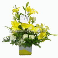 Cam kare vazo içerisine sarı ve beyaz kum süsü ,Lilyum ,beyaz Güller , Panjur garnitürlü hazırlanmış şık bir masa arajman çiçek<br><img src=../UserMods/new.gif><br>